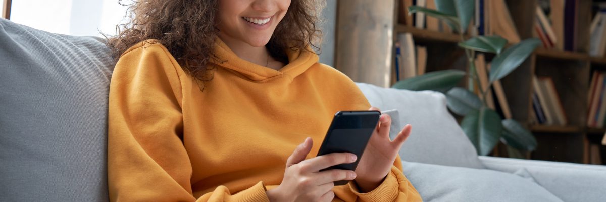 Happy,Millennial,Hispanic,Teen,Girl,Checking,Social,Media,Holding,Smartphone